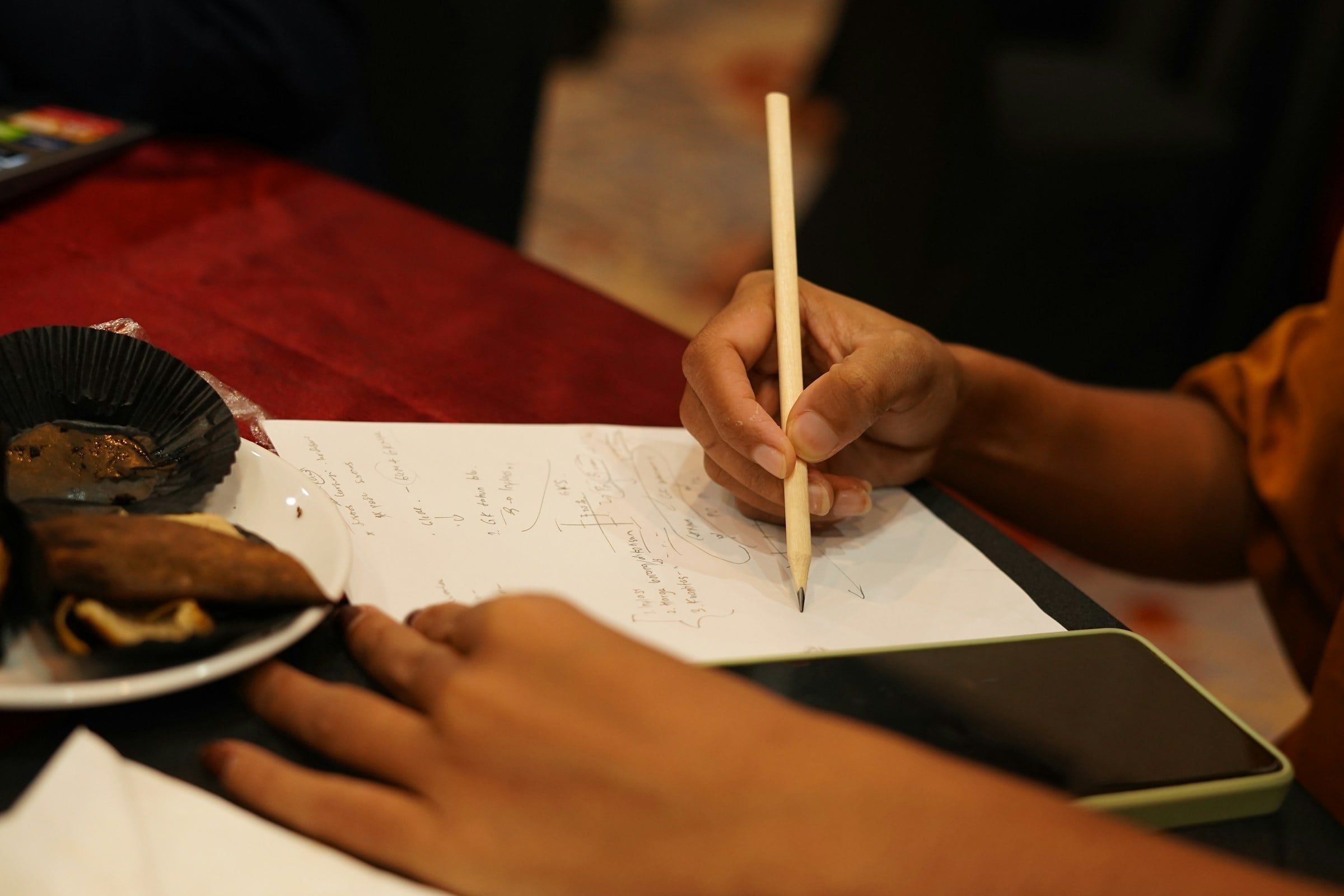 Une main qui prend des notes au crayon sur une feuille.