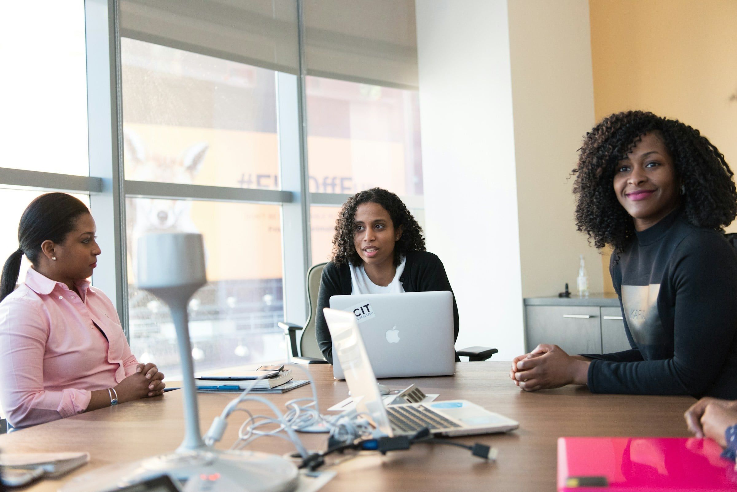 Trois femmes échangent autour d’une table de travail.